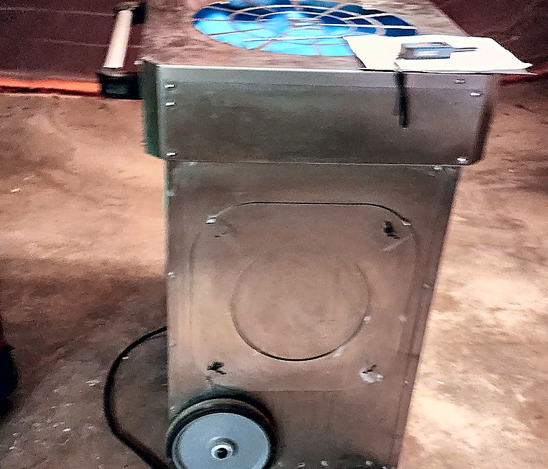 Stainless steel commercial dehumidifier and air-handling unit on wheels with a digital moisture meter on top in a basement