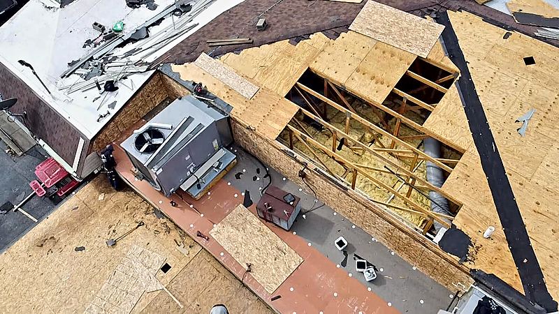 Aerial view of a rooftop HVAC unit beside exposed roof decking and open roof framing during a roofing project